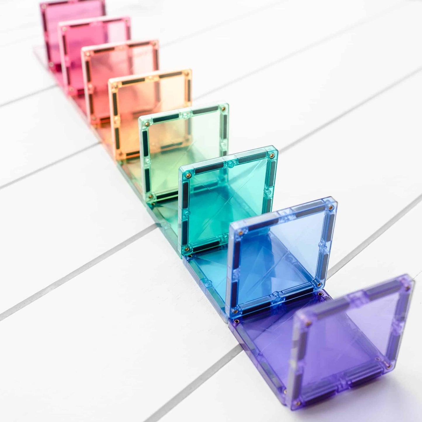 Row of colorful transparent magnetic tiles on a light gray background
