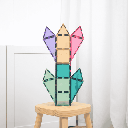 Colorful magnetic tiles plant structure on a wooden stool against a white curtain background