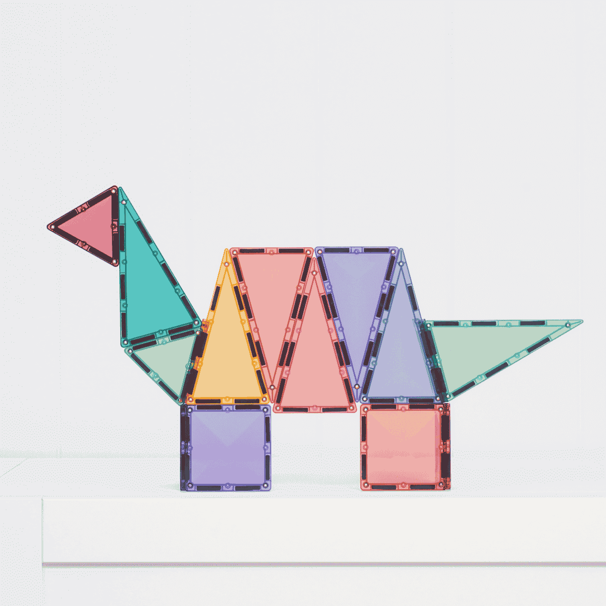 Colorful gmagnetic tiles arranged to form a dinosaur on a white background