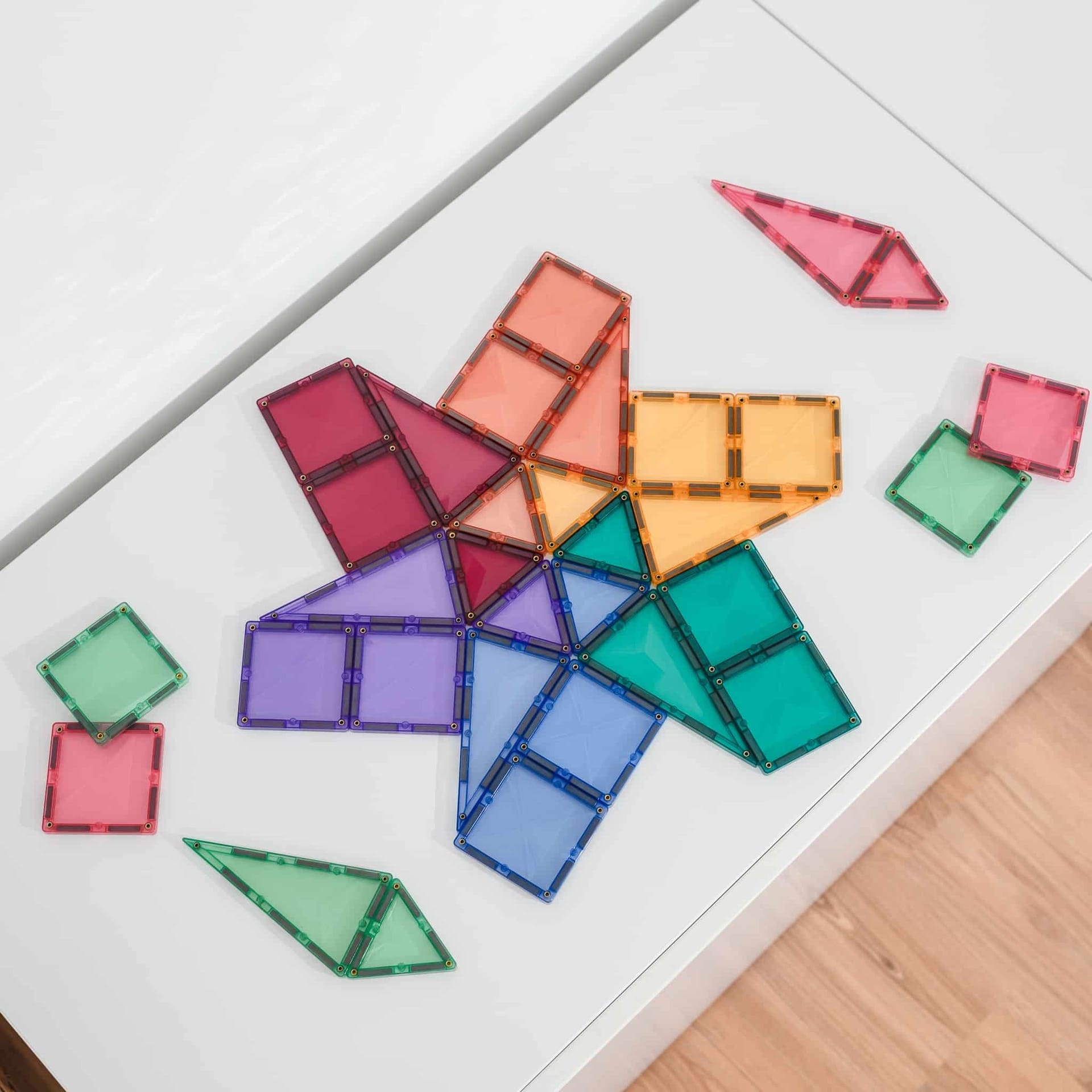 Colorful geometric transparent magnetic tiles on a white surface
