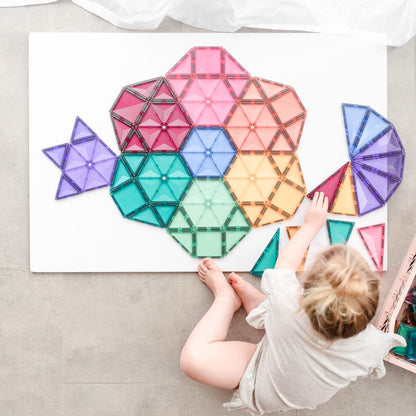 Child playing with colorful geometric magnetic tiles on a white surface